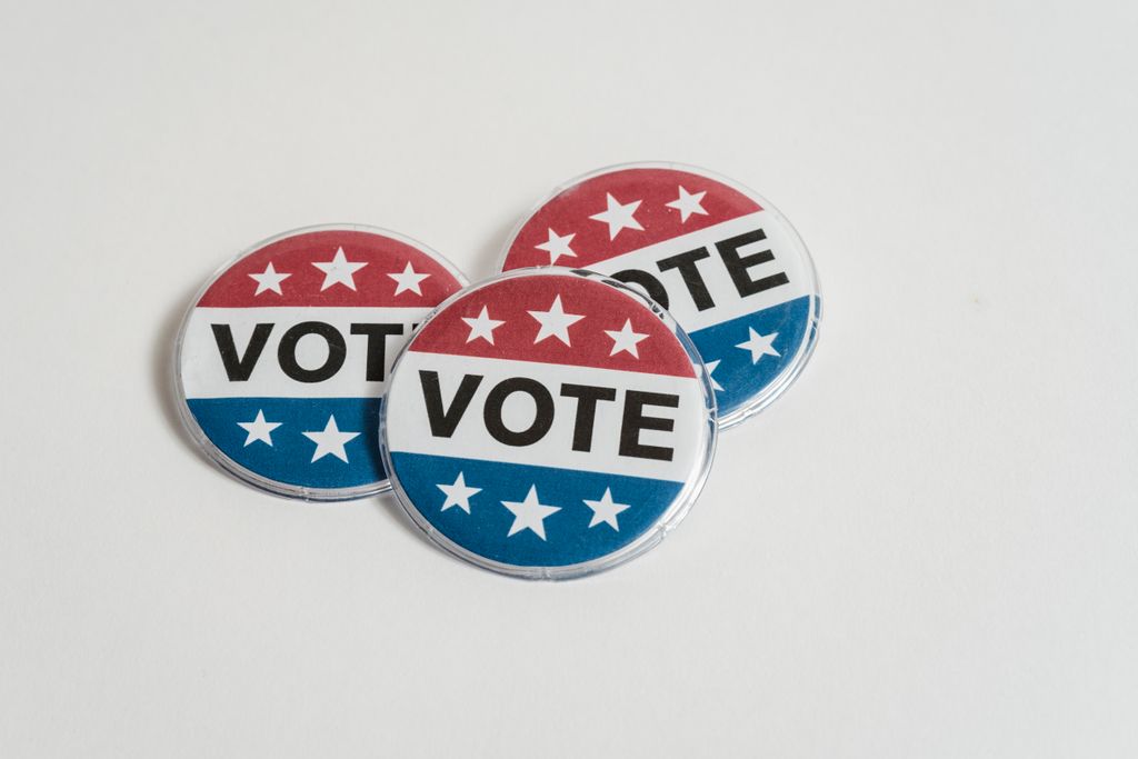 Red, white, and blue voting badges promoting elections on a clean white background.